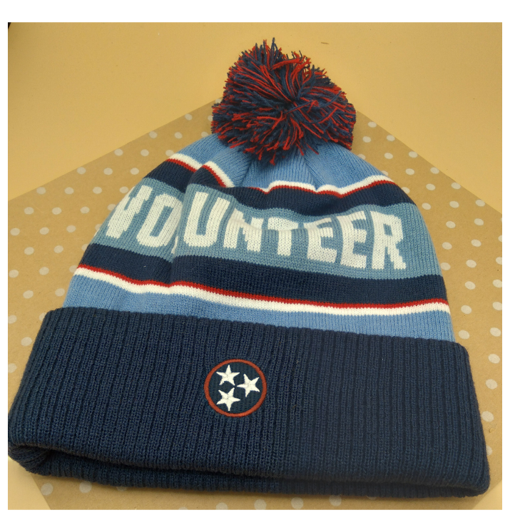 Knitted hat with 'Volunteer' text on a beige background